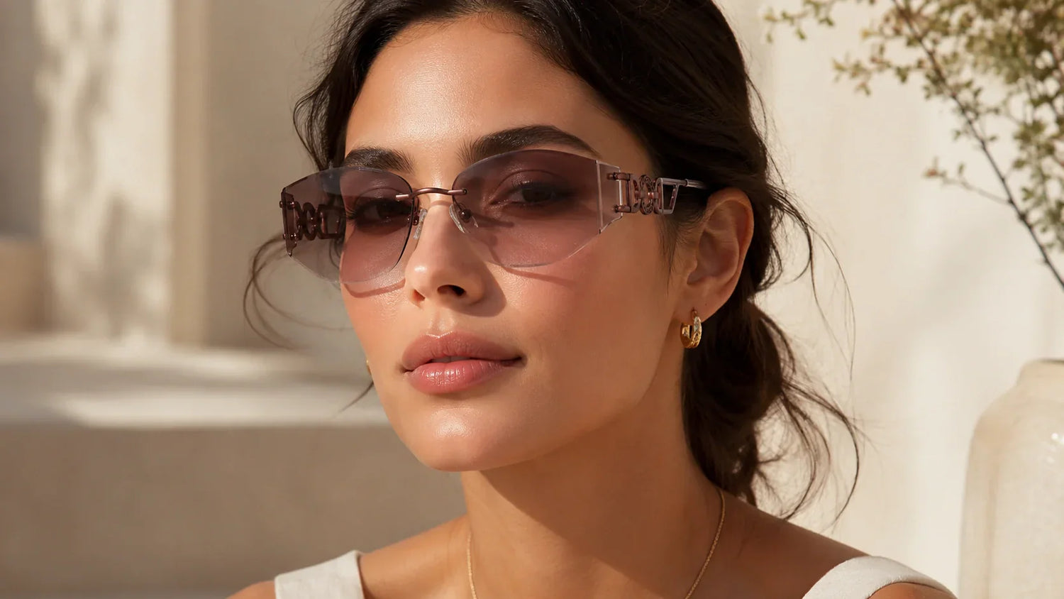Woman wearing lightweight rimless sunglasses that visually balance prominent facial features.