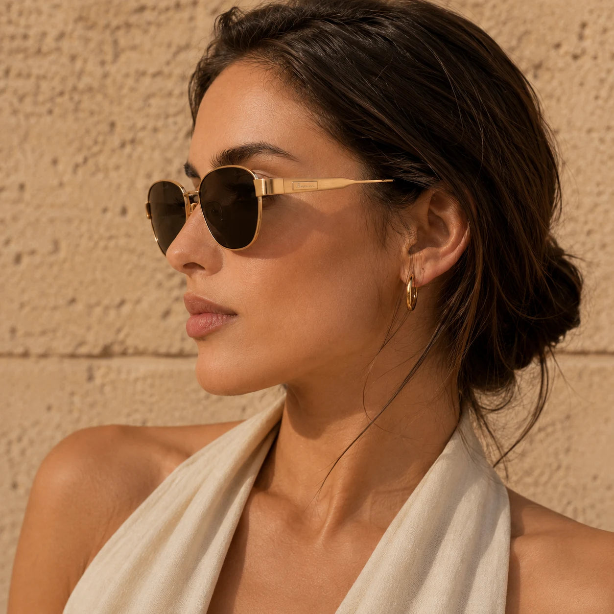 Side profile of woman wearing BAPORSSA Aurelia sunglasses with gold metal frame, smoke lenses, and refined temple detail