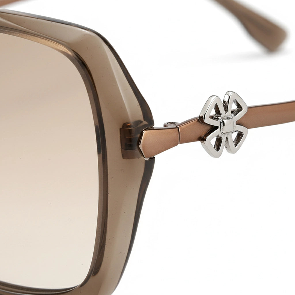 Close-up of sunglasses with a decorative metal bow on the arm against a white background