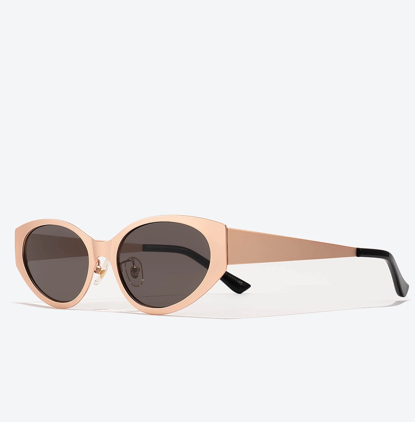 Sunglasses with a rose gold frame and dark lenses on a white background