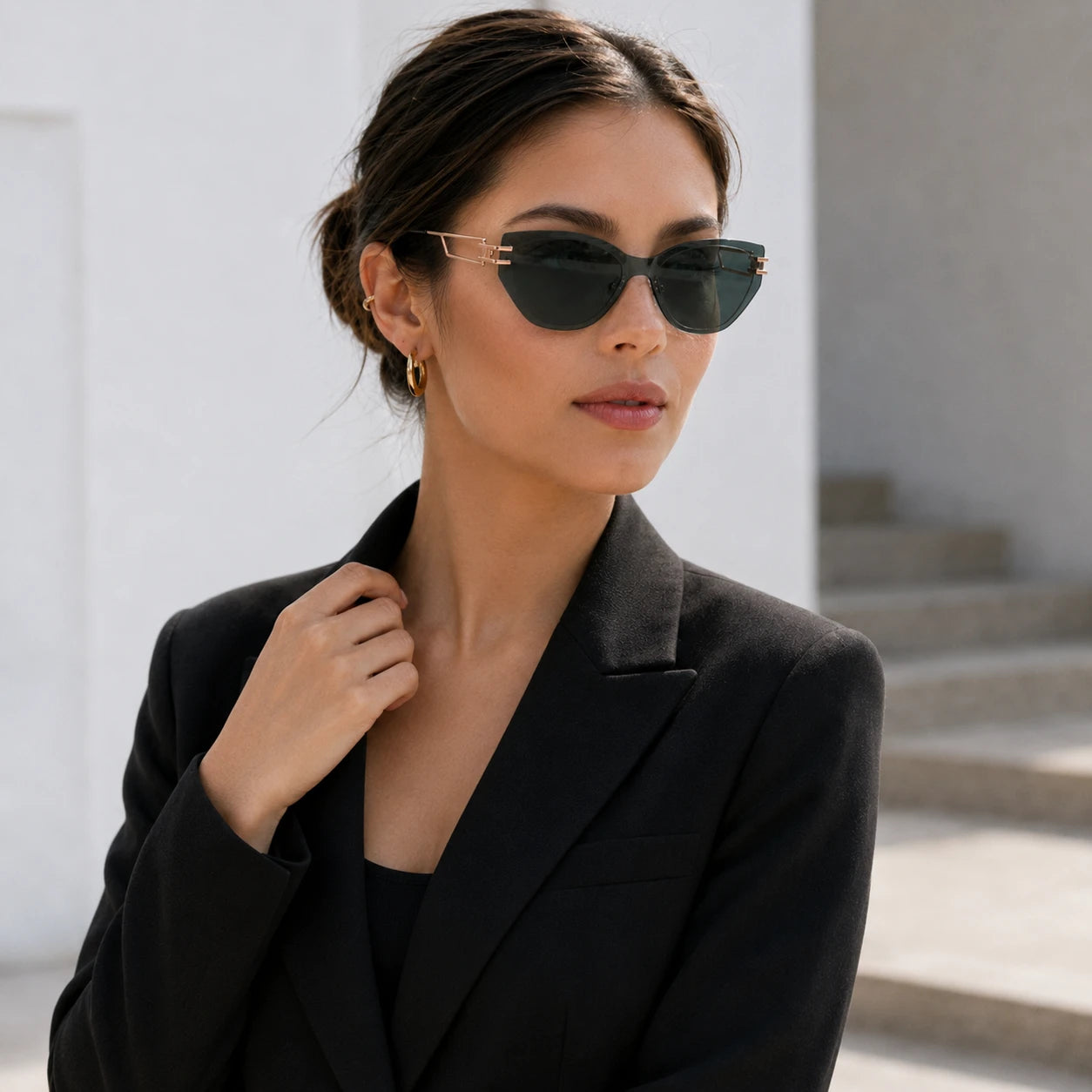 Editorial portrait of a woman in a black blazer looking to the side, wearing Baporssa Edge translucent dark green sunglasses with gold temples.