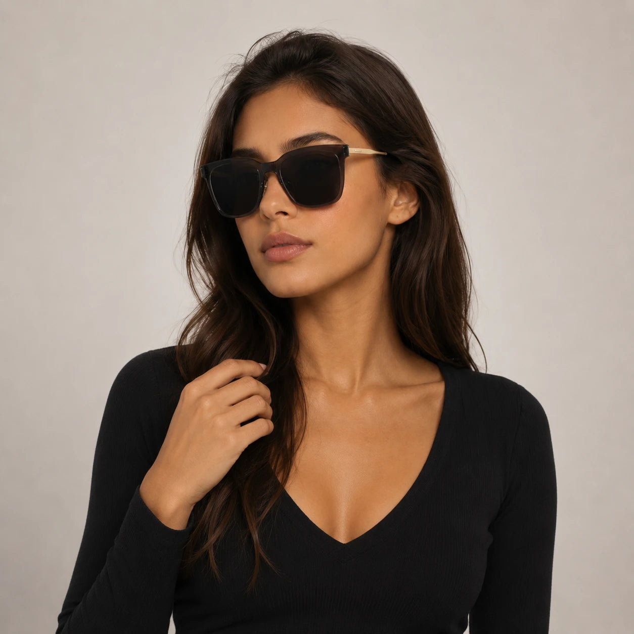 Three-quarter portrait of a woman wearing Baporssa Halo oversized grey sunglasses paired with a black V-neck top.