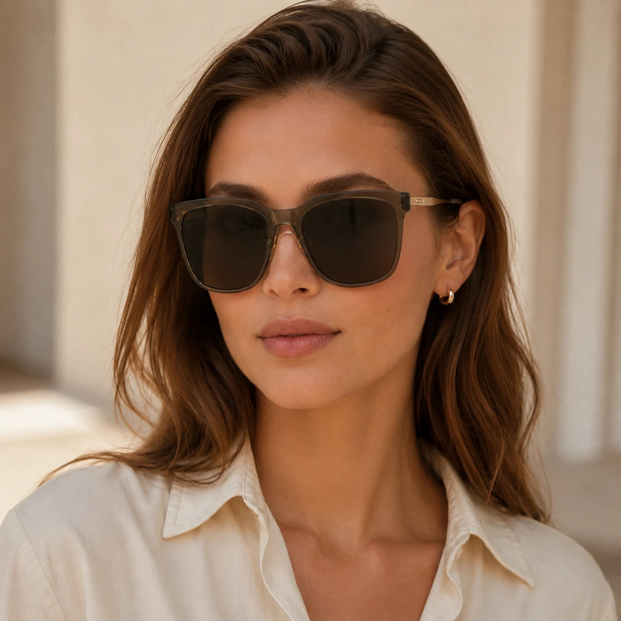 Front close-up portrait of a woman wearing Baporssa Halo square sunglasses, featuring translucent grey frames and gold hardware.