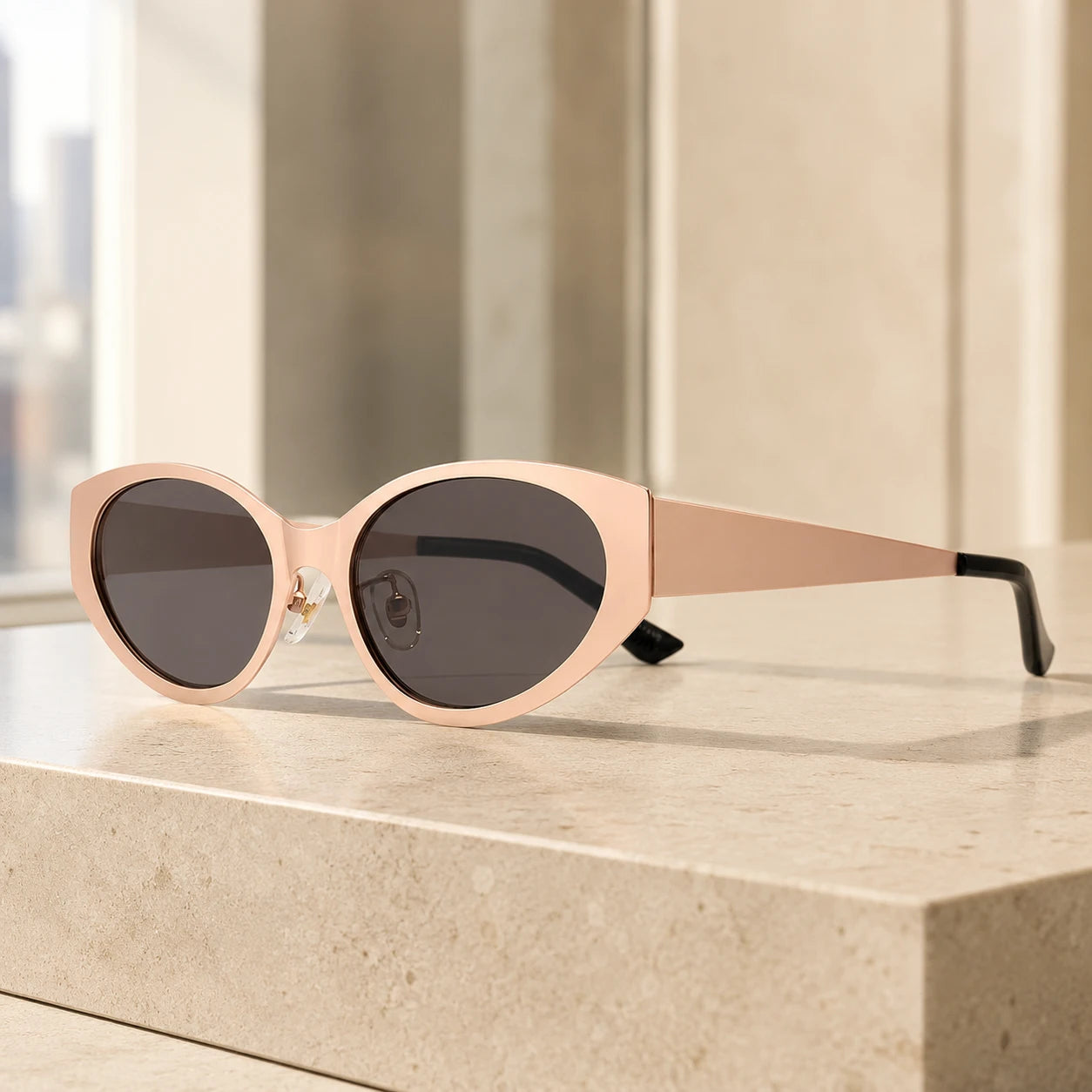 Lyra designer cat-eye sunglasses with nude beige frames and dark lenses on a sunlit marble counter.