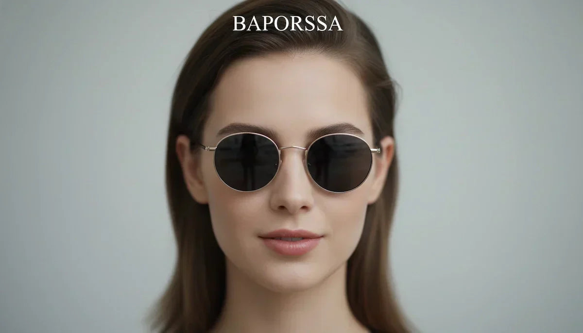A close-up portrait of a woman with long brown hair wearing Baporssa gold-framed round sunglasses with dark lenses, against a light gray background, with the Baporssa logo at the top.