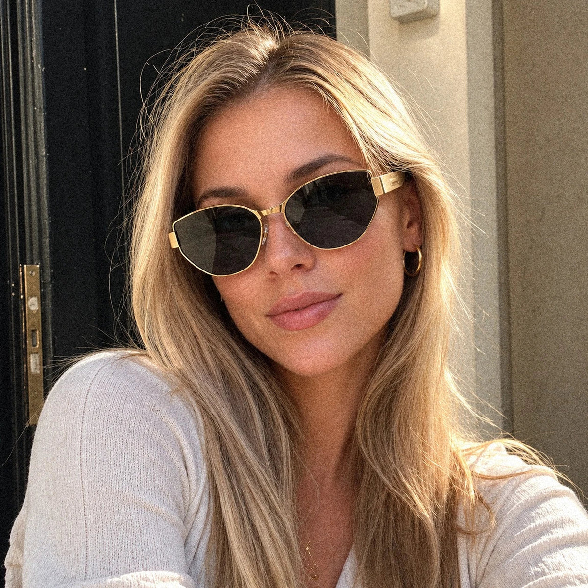 Woman outdoors wearing BAPORSSA Onyx titanium cat-eye sunglasses in Black Gold