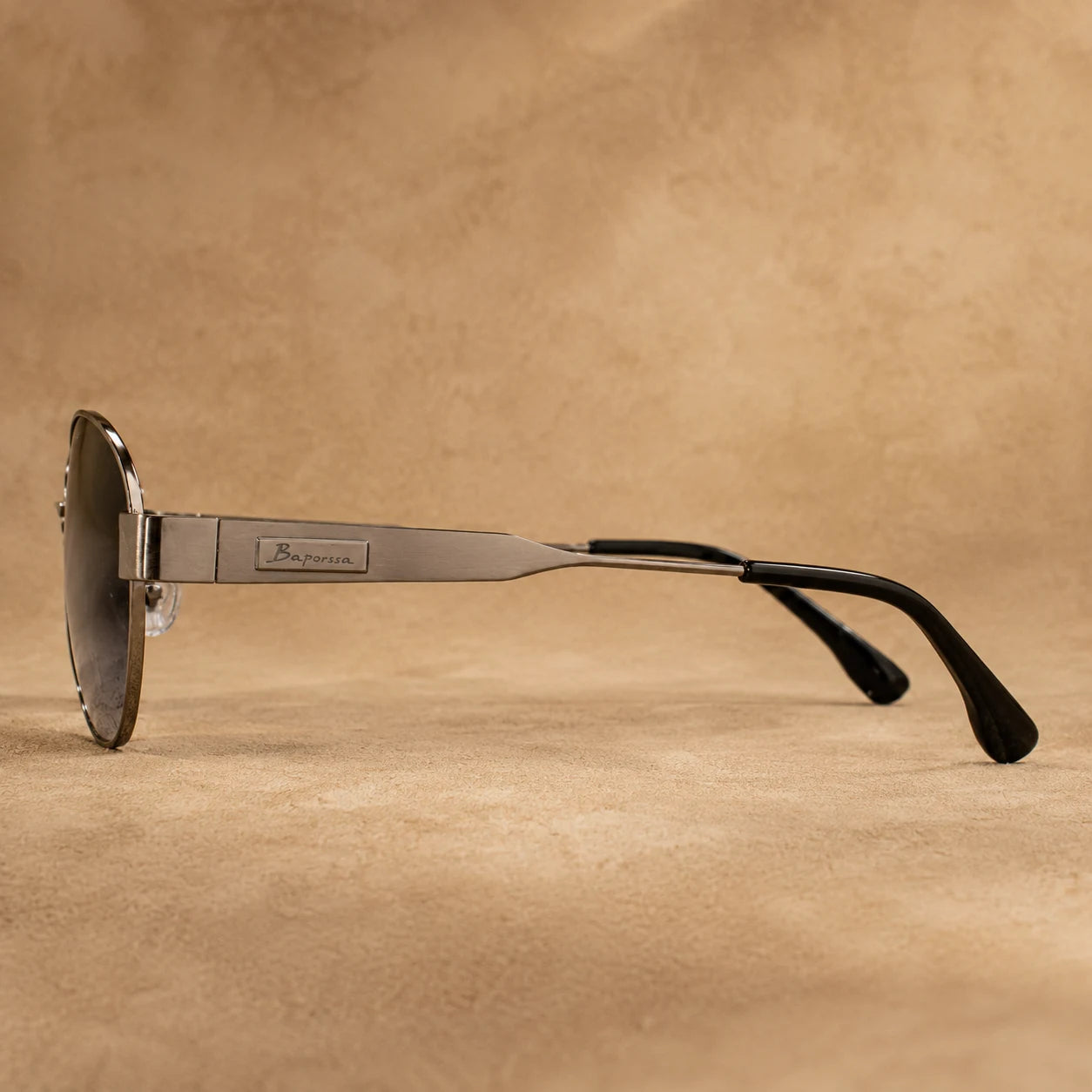 Side view of BAPORSSA Aurelia sunglasses with gunmetal metal temple, logo detail, black temple tips, and lightweight frame design