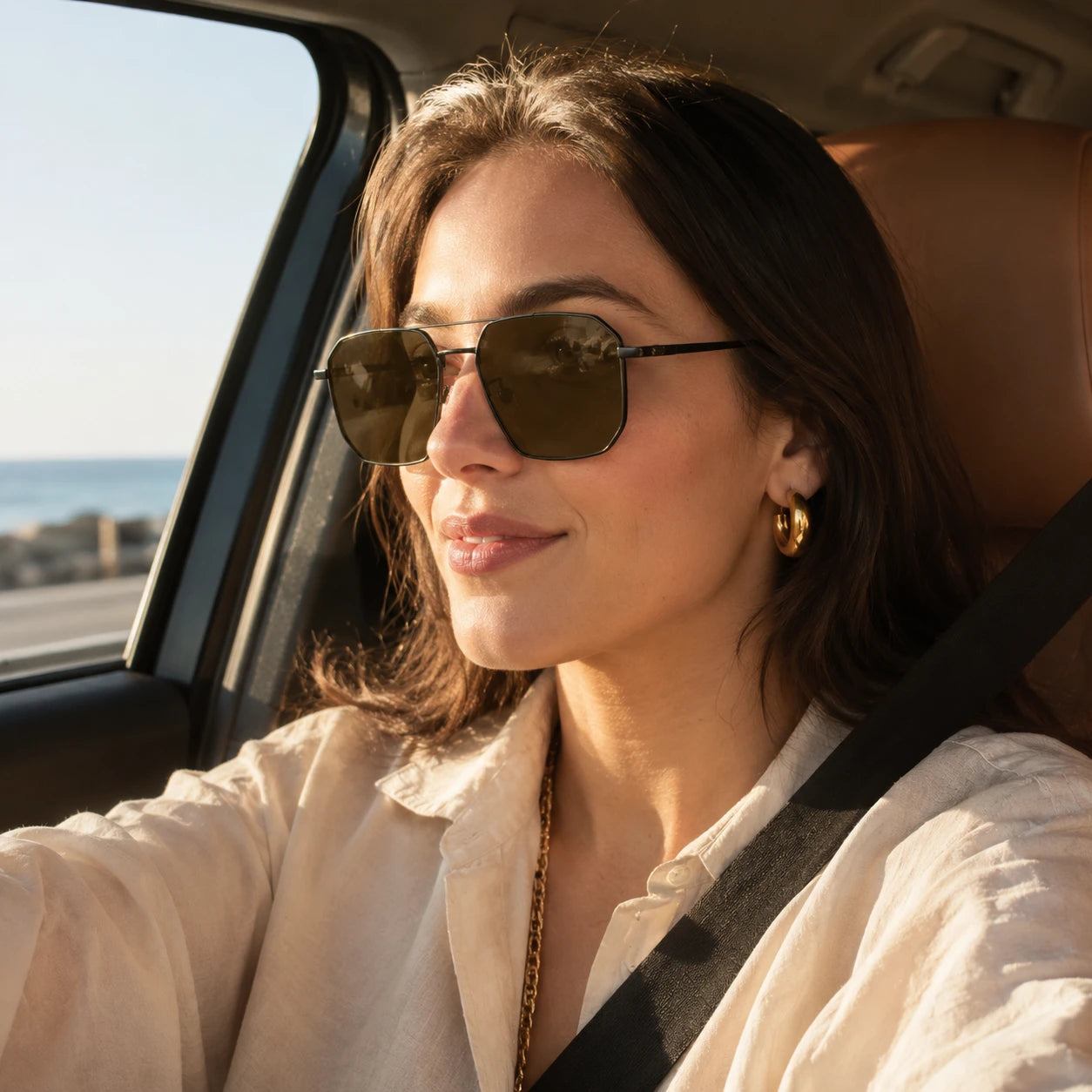 Female driver wearing BAPORSSA Shift sunglasses with dark adaptive lenses while driving near the coast