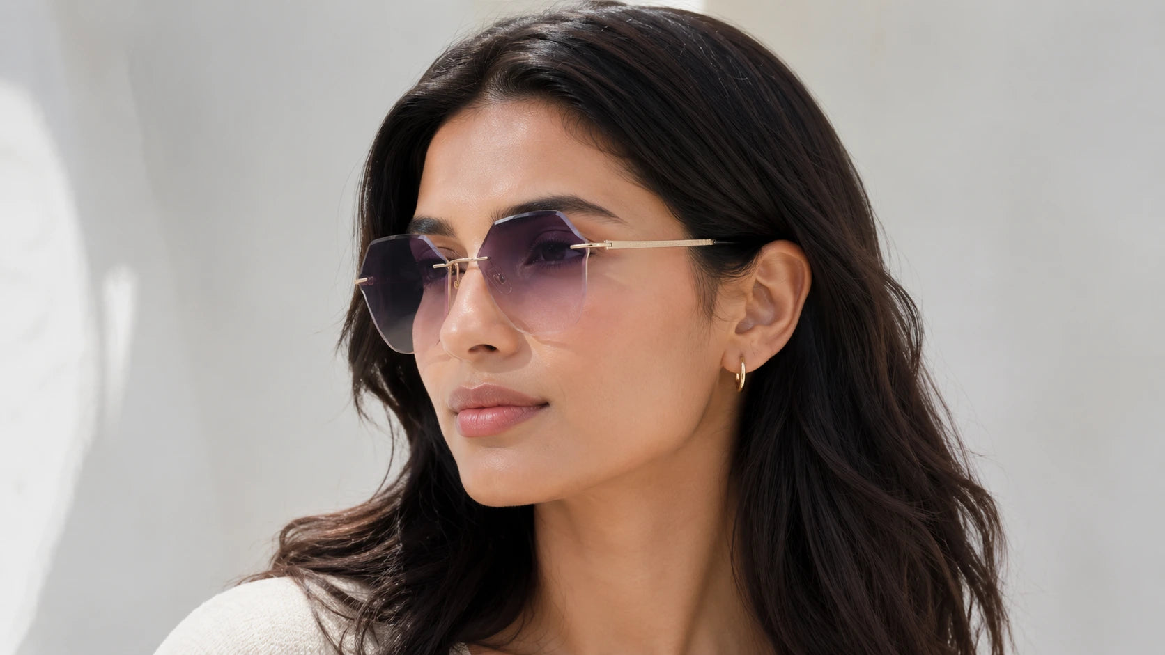 A brunette woman wearing BAPORSSA rimless sunglasses with hexagonal
     purple gradient lenses in a bright outdoor setting.