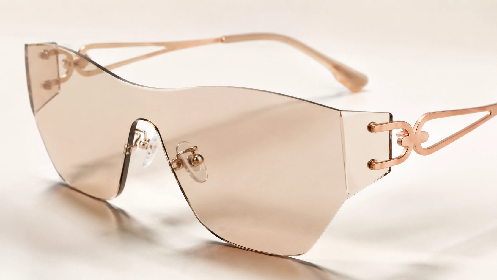 A high-resolution studio shot of BAPORSSA rimless sunglasses featuring
     amber-tinted lenses and intricate gold geometric temple design on a clean,
     light surface