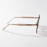 Eyeglasses with a gold frame on a light gray background