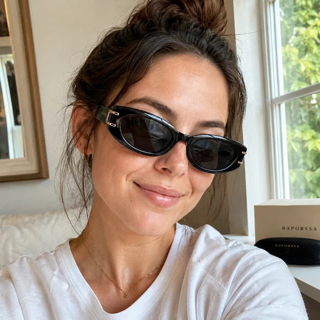 Woman taking an indoor selfie wearing black sunglasses with BAPORSSA packaging in the background.