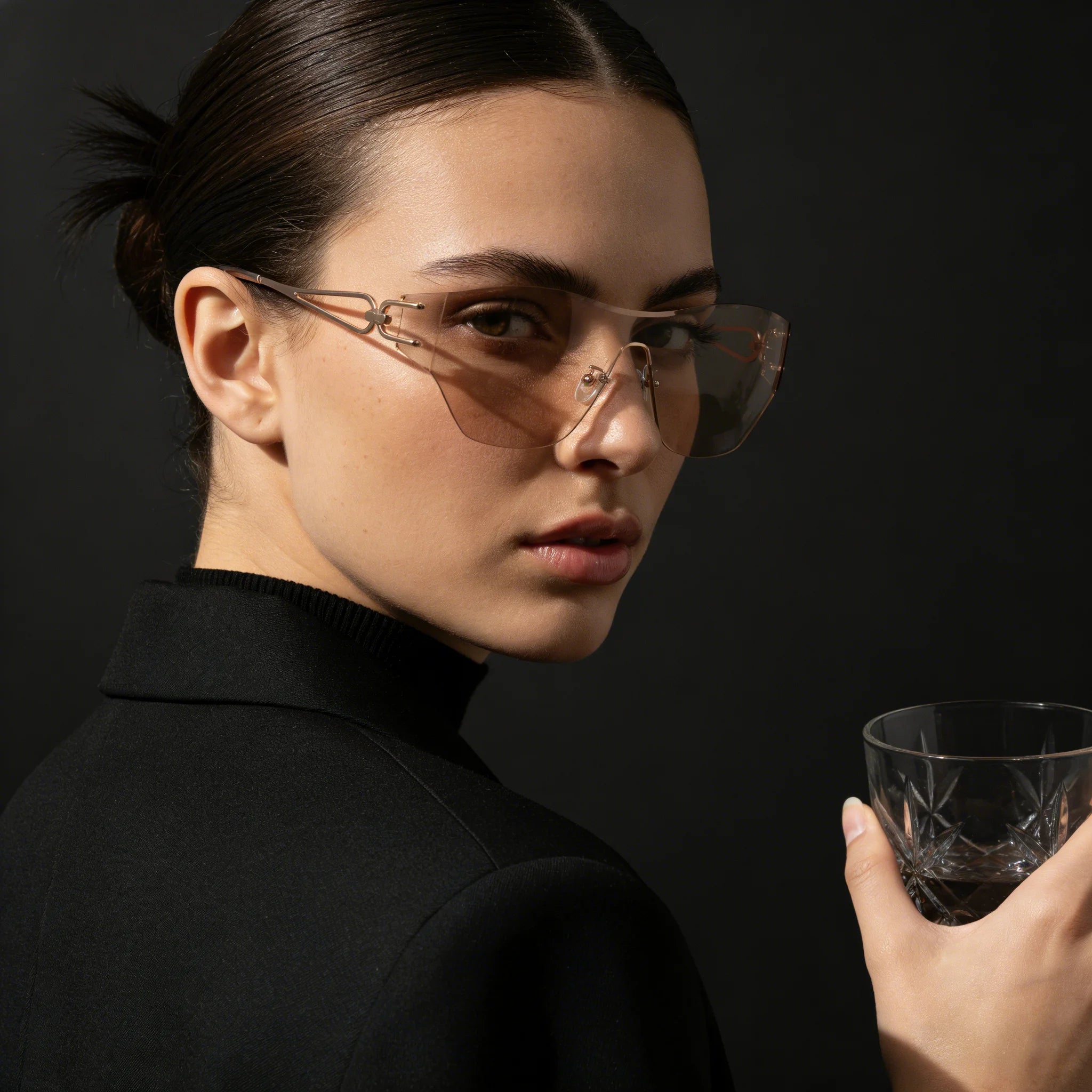Woman wearing sunglasses and holding a glass against a dark background1