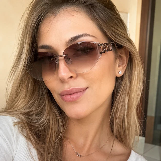 Woman taking an indoor selfie wearing brown gradient rimless sunglasses with decorative temple details.