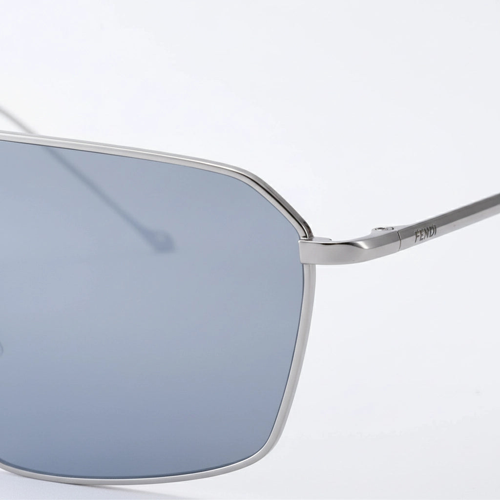 Minimalist oversized flat-top sunglasses with thin silver metal frames and light gray tinted lenses, displayed against a clean white background, showcasing modern, sleek design.