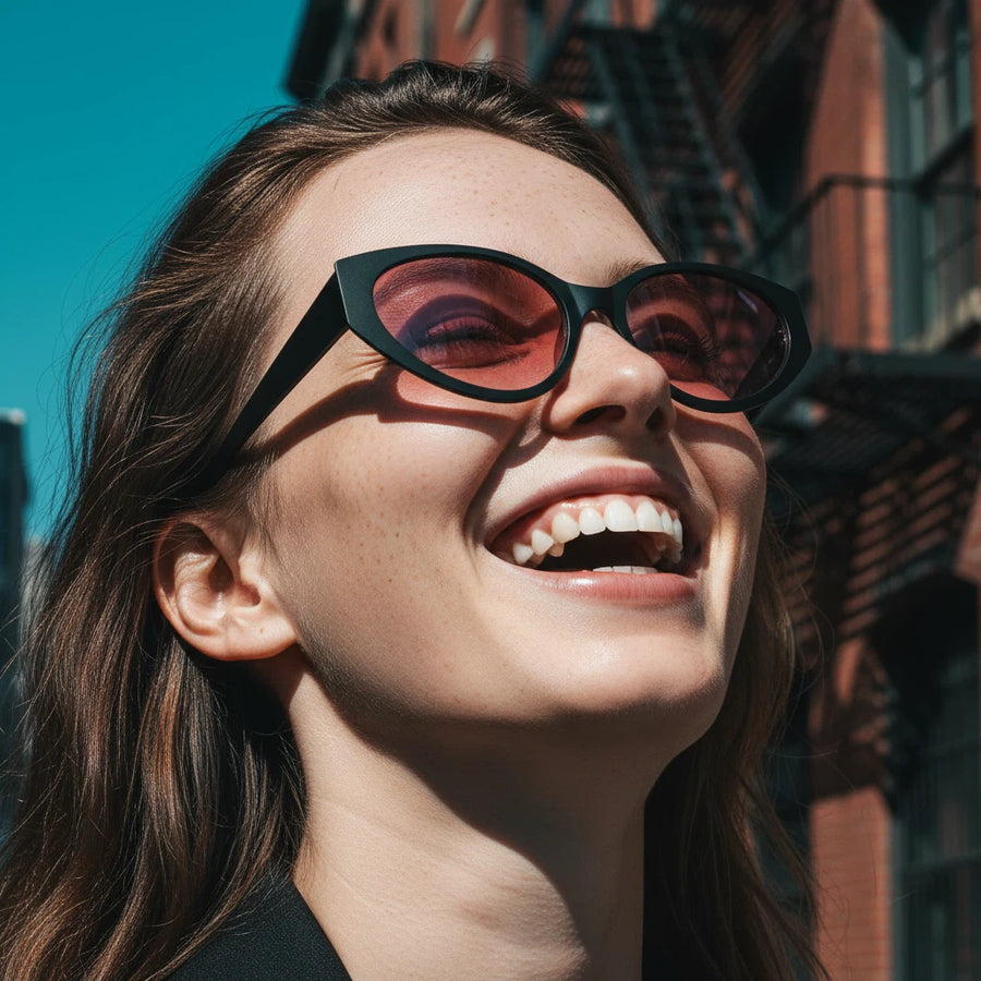 Woman wearing black cat-eye sunglasses with a blurred urban background
