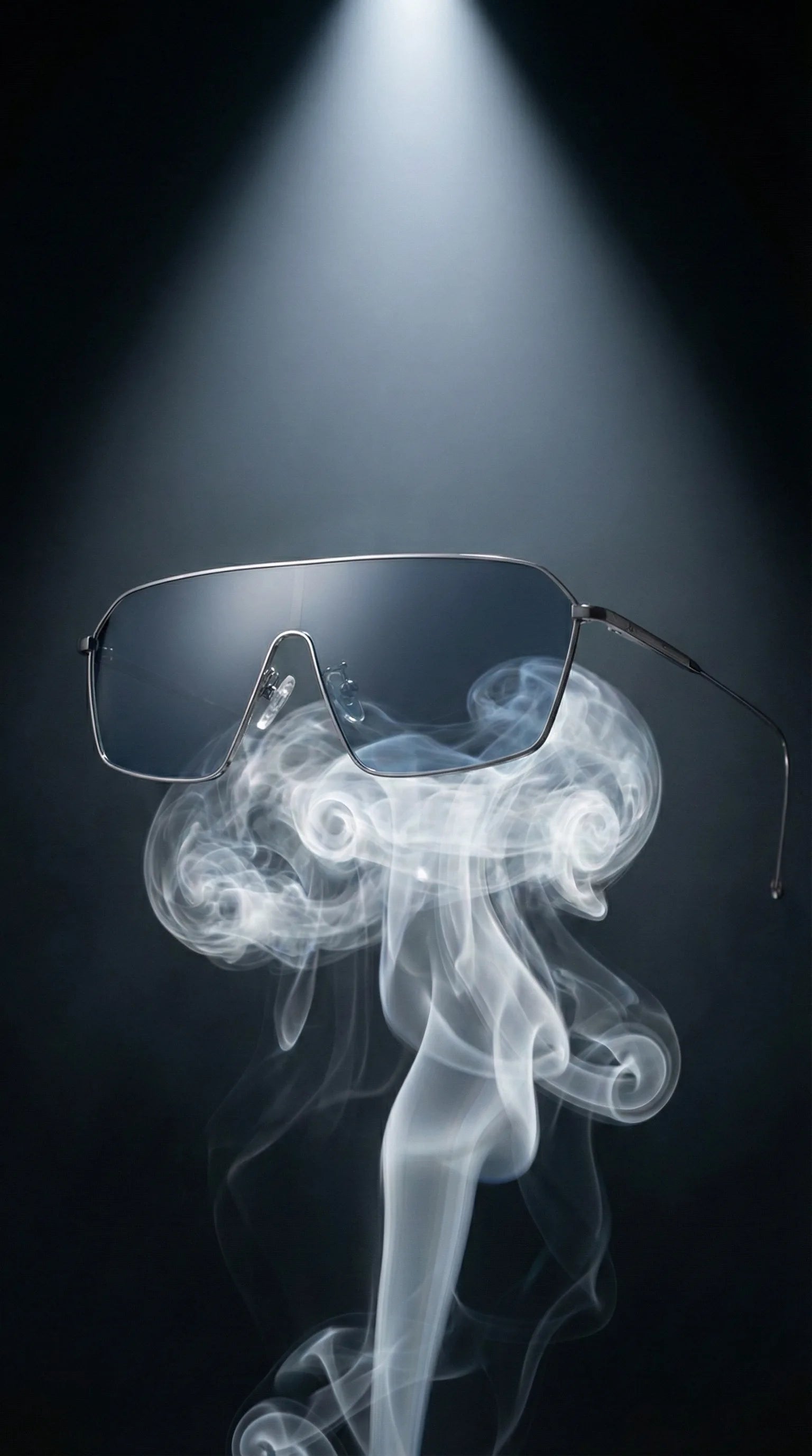 The titanium sunglasses are resting on top of a rising curl of smoke in a dark studio. The smoke supports the glasses, emphasizing extreme lightness.
