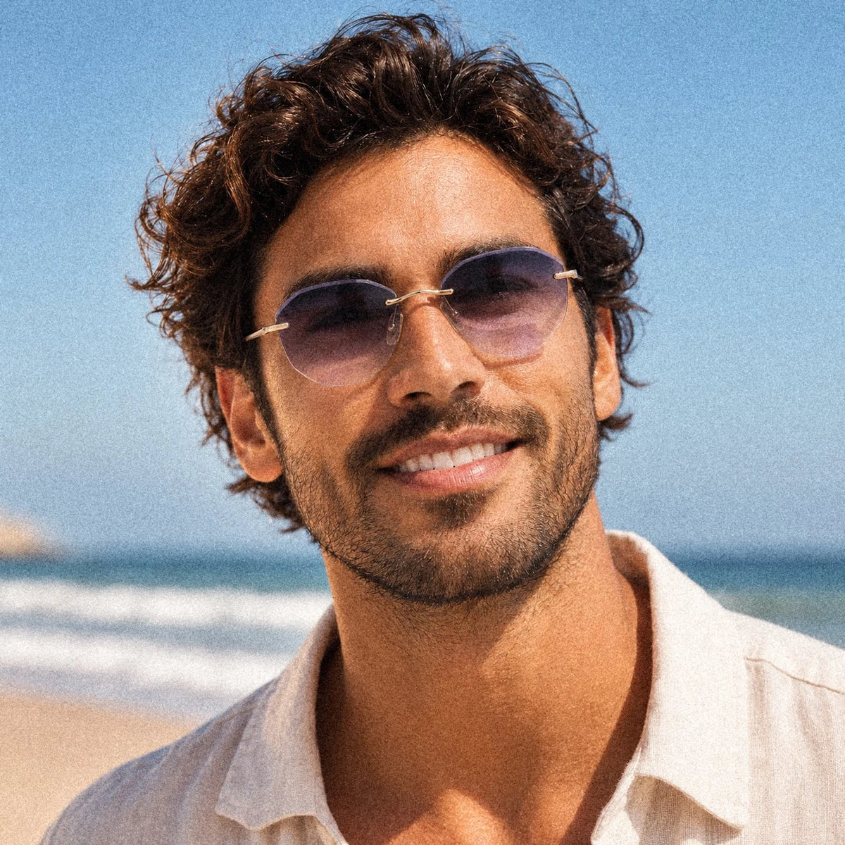 BAPORSSA Backbone rimless sunglasses in Crystal Grey, worn by a model by the ocean