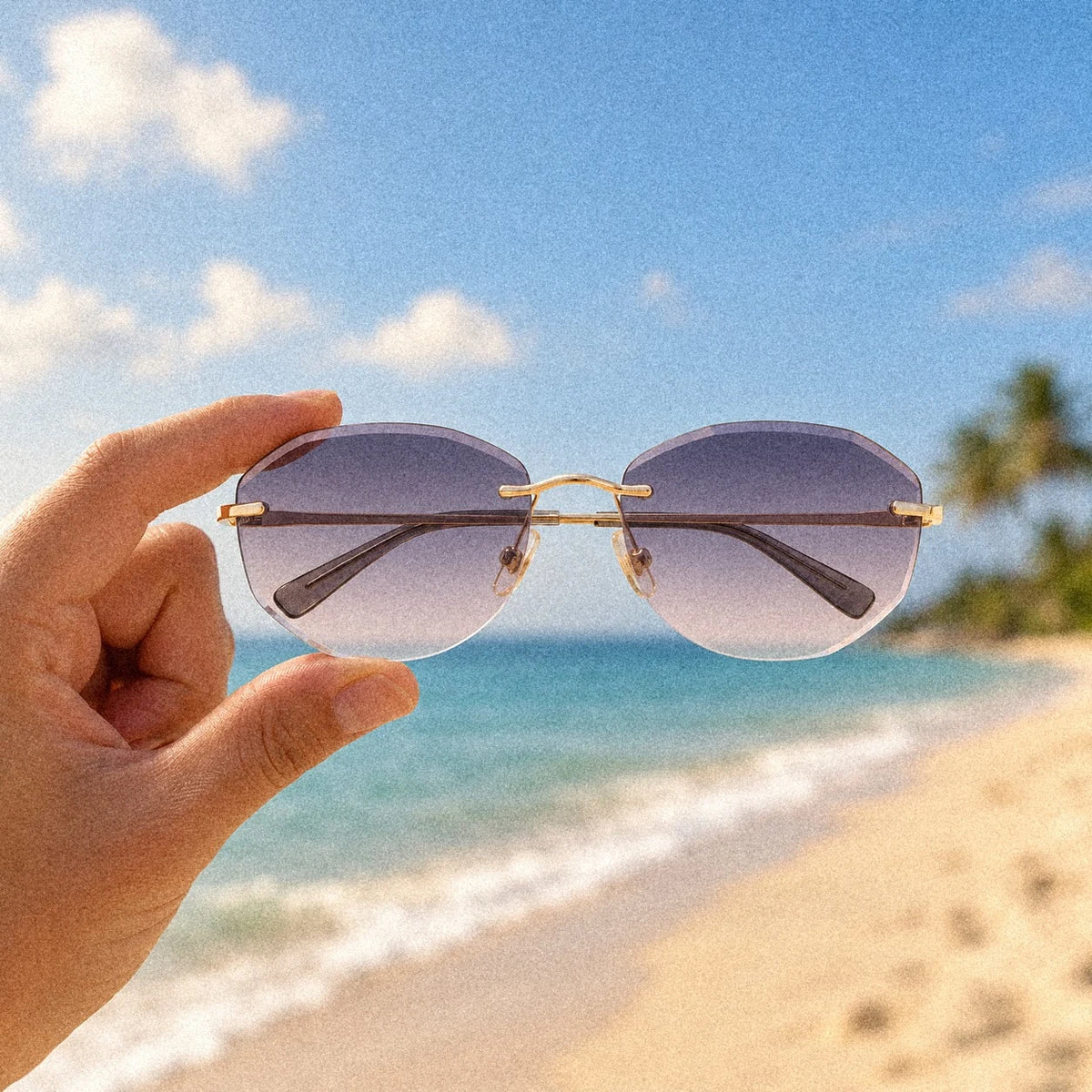 Hand holding BAPORSSA Backbone rimless sunglasses in Crystal Grey on a sunny beach
