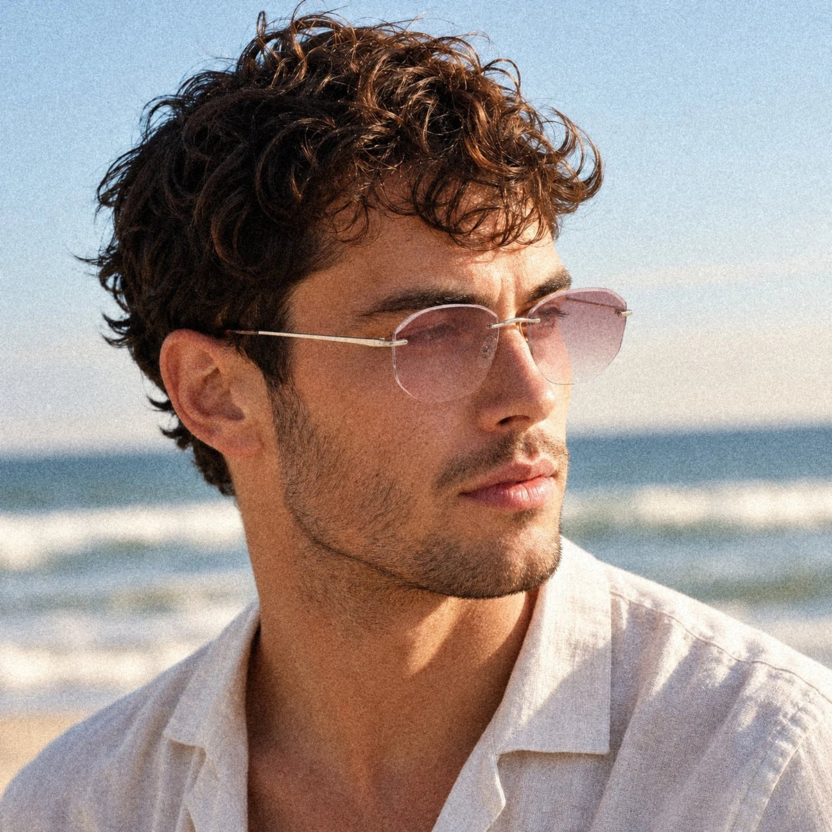 Male model wearing Backbone Luminous Rose rimless sunglasses at the beach