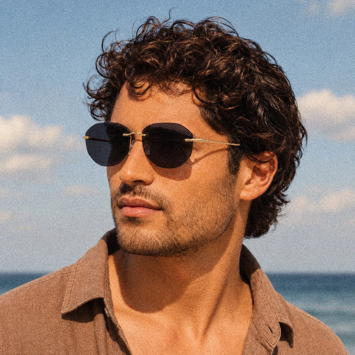 Male model wearing Backbone Noir Carbon rimless sunglasses at the beach