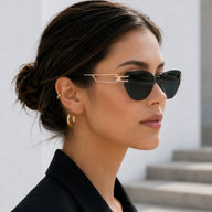 Side profile of a woman with her hair in a bun, showcasing the elegant gold geometric temple design of Baporssa Edge dark green sunglasses.