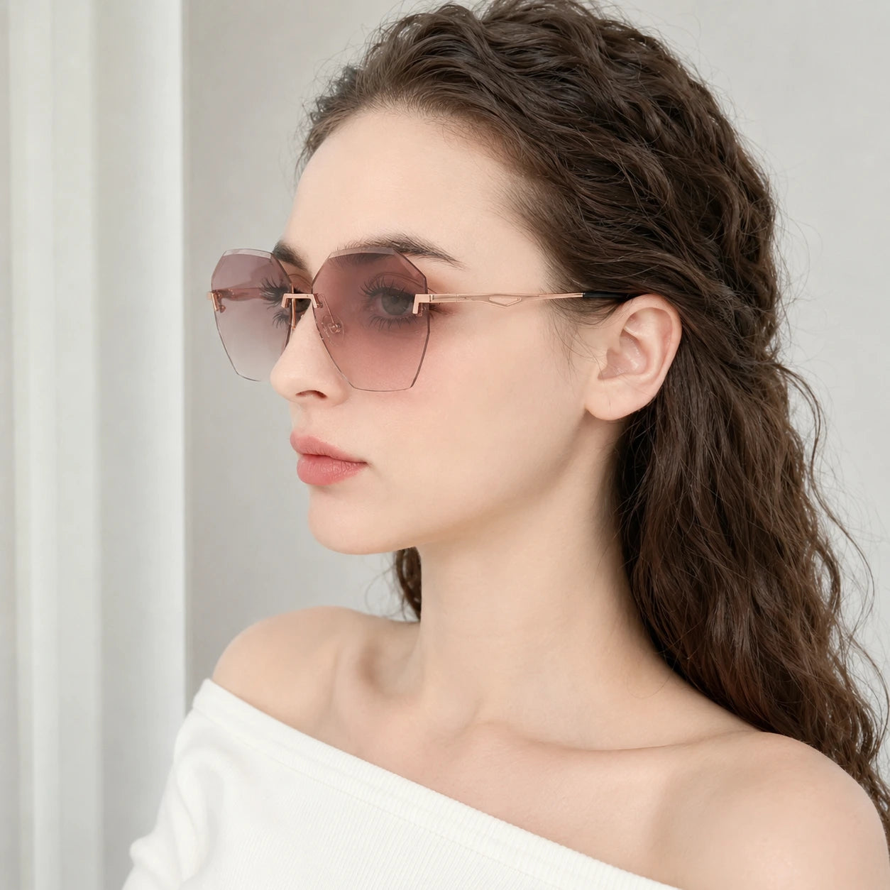 Side profile portrait of a woman wearing Baporssa Glow sunglasses, highlighting the sleek rose gold metal temple arm and pink gradient lens shape.