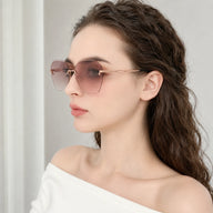 Side profile portrait of a woman wearing Baporssa Glow sunglasses, highlighting the sleek rose gold metal temple arm and pink gradient lens shape.