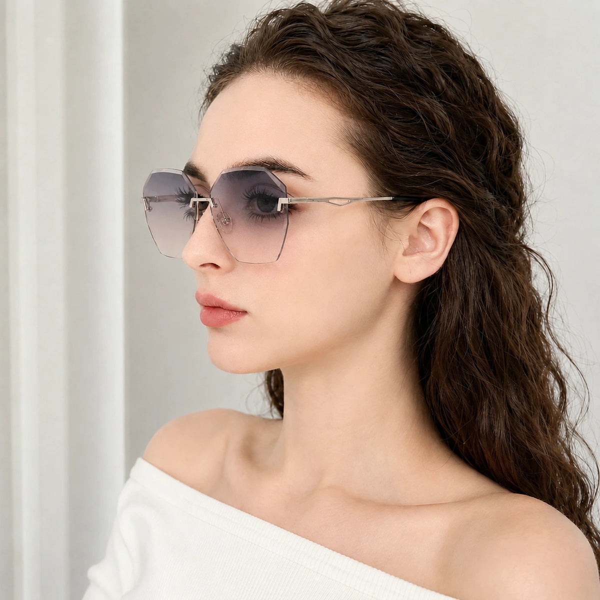 Side profile portrait of a woman wearing BAPORSSA Glow sunglasses, highlighting the elegant silver metal temple arm and the blue-grey gradient lens.