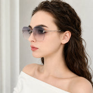Side profile portrait of a woman wearing Baporssa Glow sunglasses, highlighting the elegant silver metal temple arm and the blue-gray gradient lens.