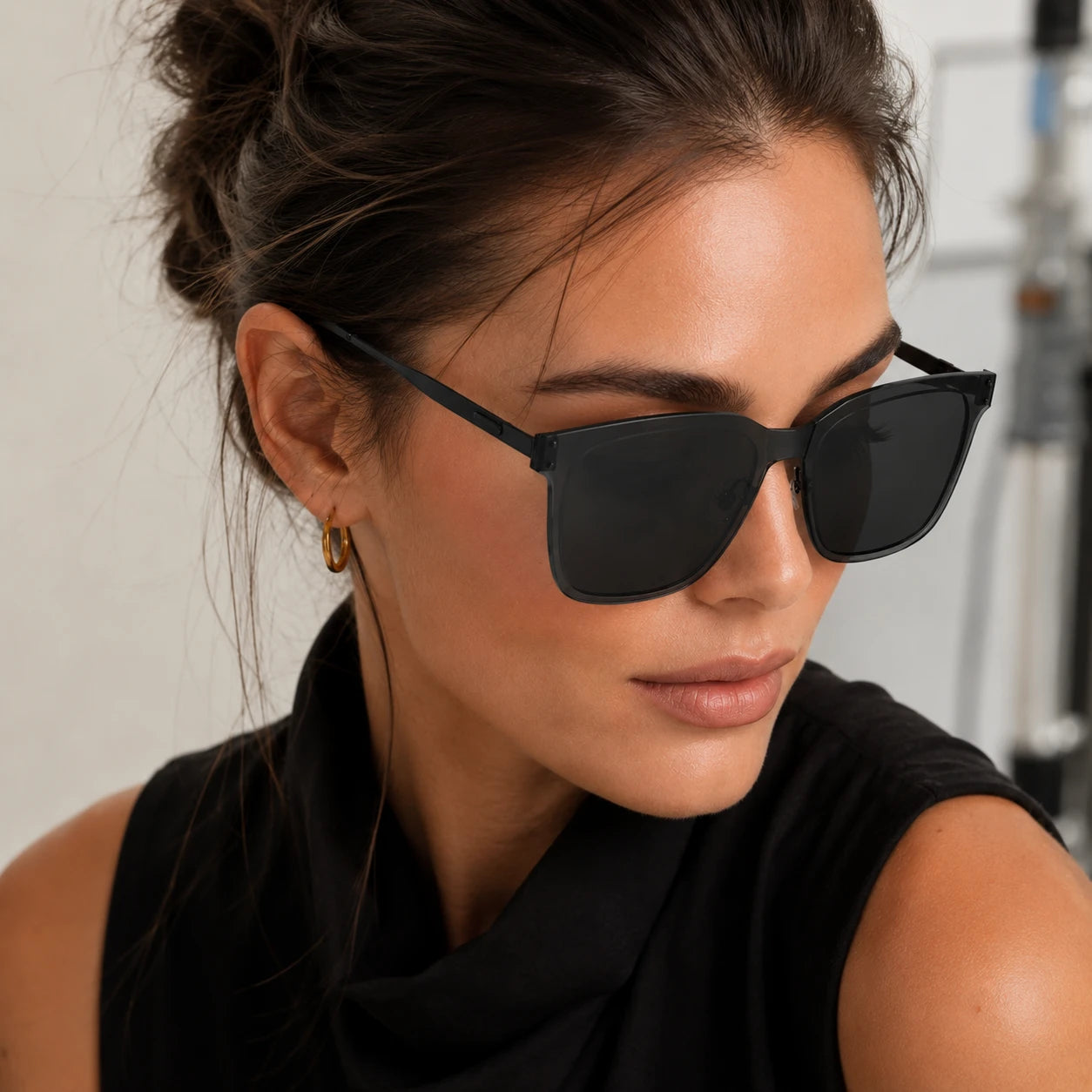 A tight close-up portrait highlighting the side and front view of the Baporssa Halo black square sunglasses frame on a female model.