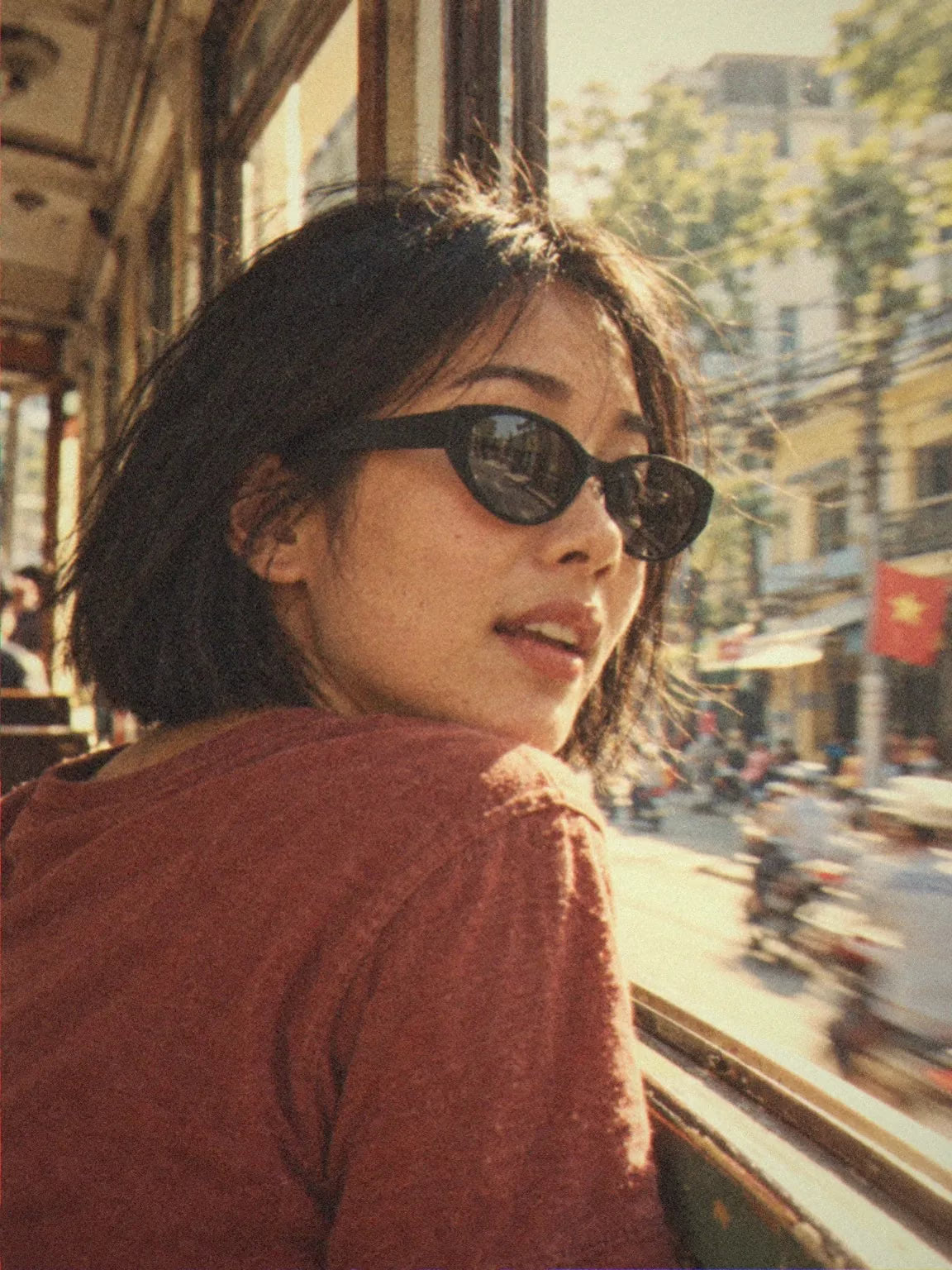 A woman in BAPORSSA Lyra black cat-eye sunglasses looking back from a tram window