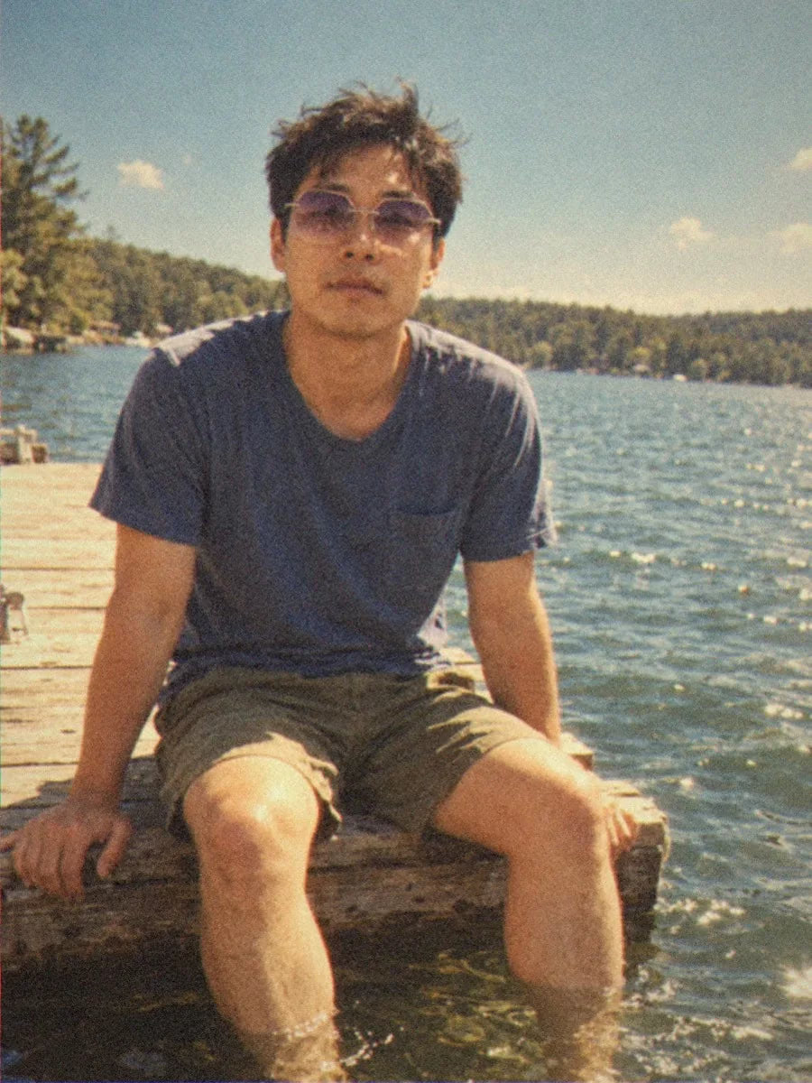 A man in BAPORSSA Air sunglasses with lavender gradient lenses sitting on a lake dock