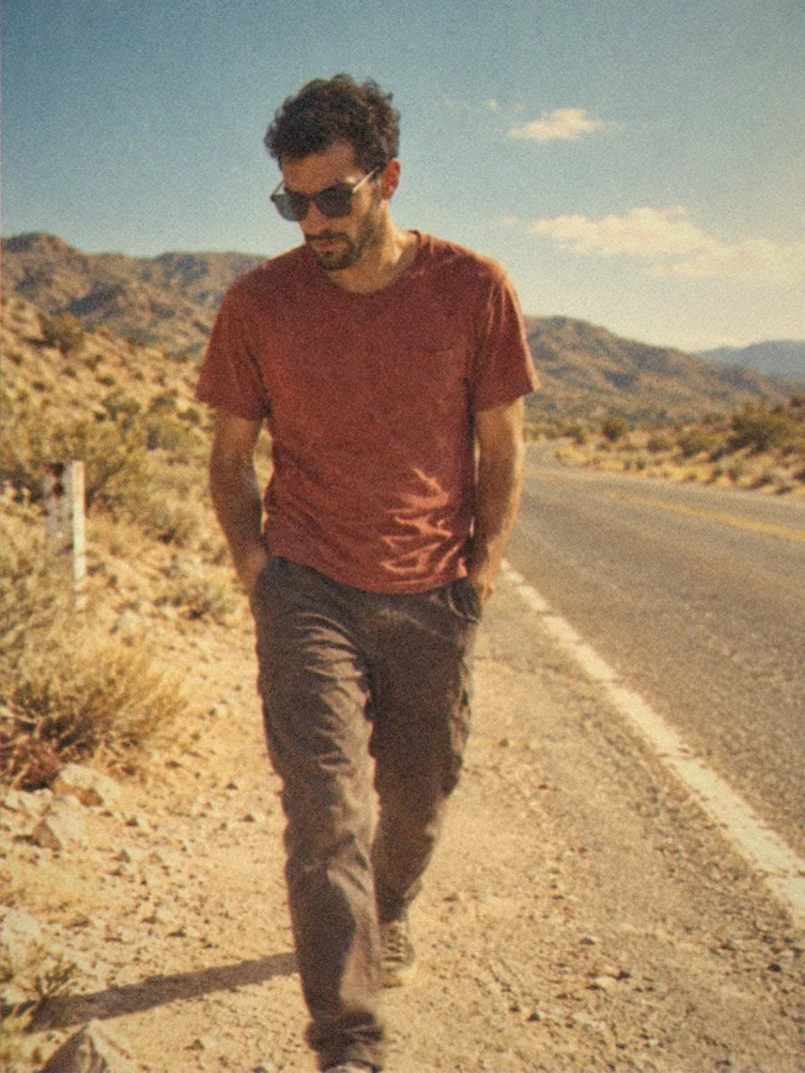 A man in BAPORSSA Halo sunglasses with smoke grey lenses walking along a desert road