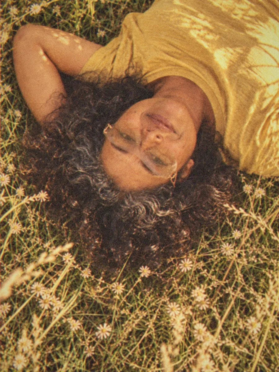 A woman in BAPORSSA Flow sunglasses with a light tea lens lying in long grass