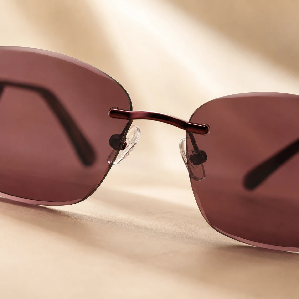 Close-up shot focusing on the polished metallic nose bridge and adjustable clear nose pads of Baporssa Muse rimless dark tinted sunglasses.