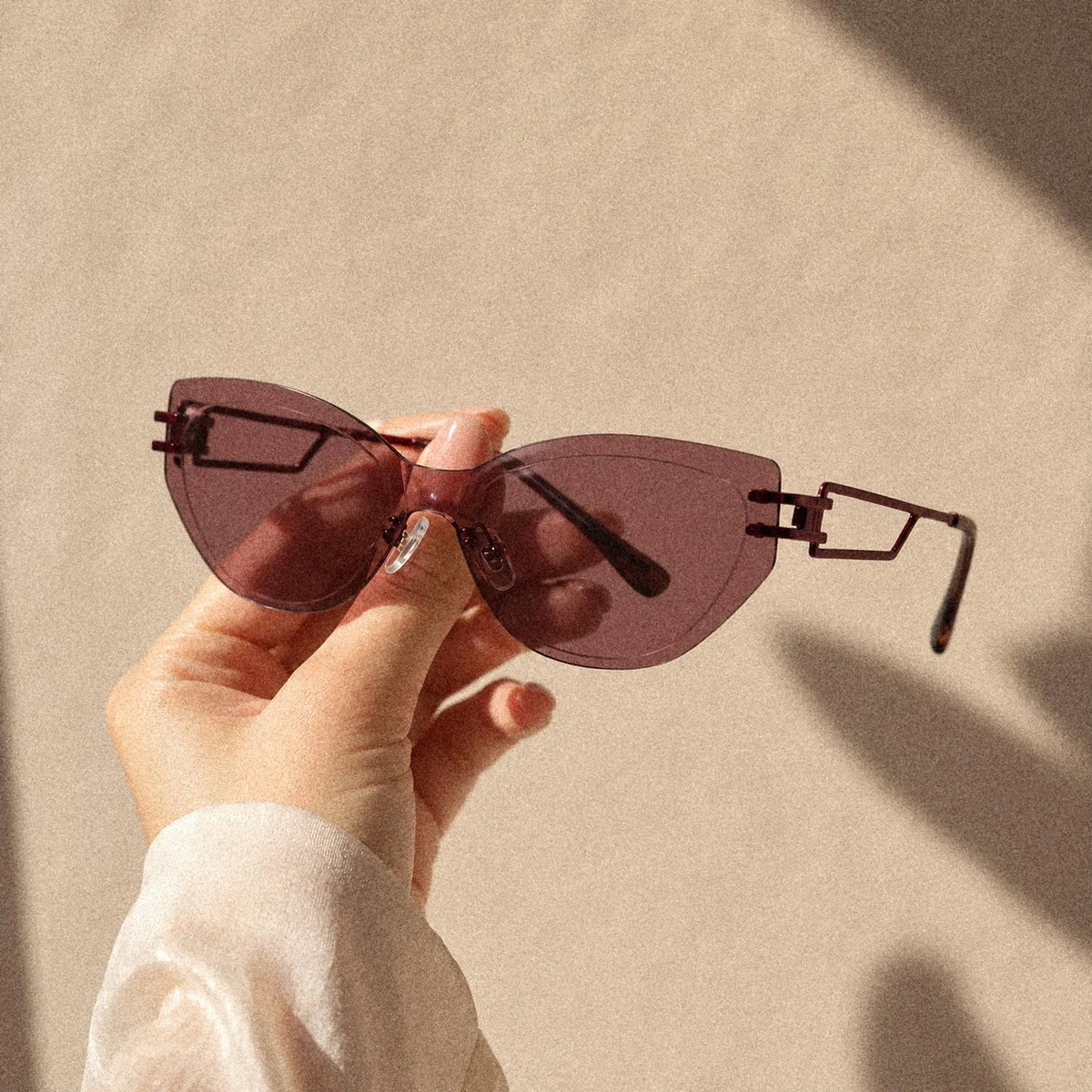Hand holding BAPORSSA Edge sunglasses in Claret