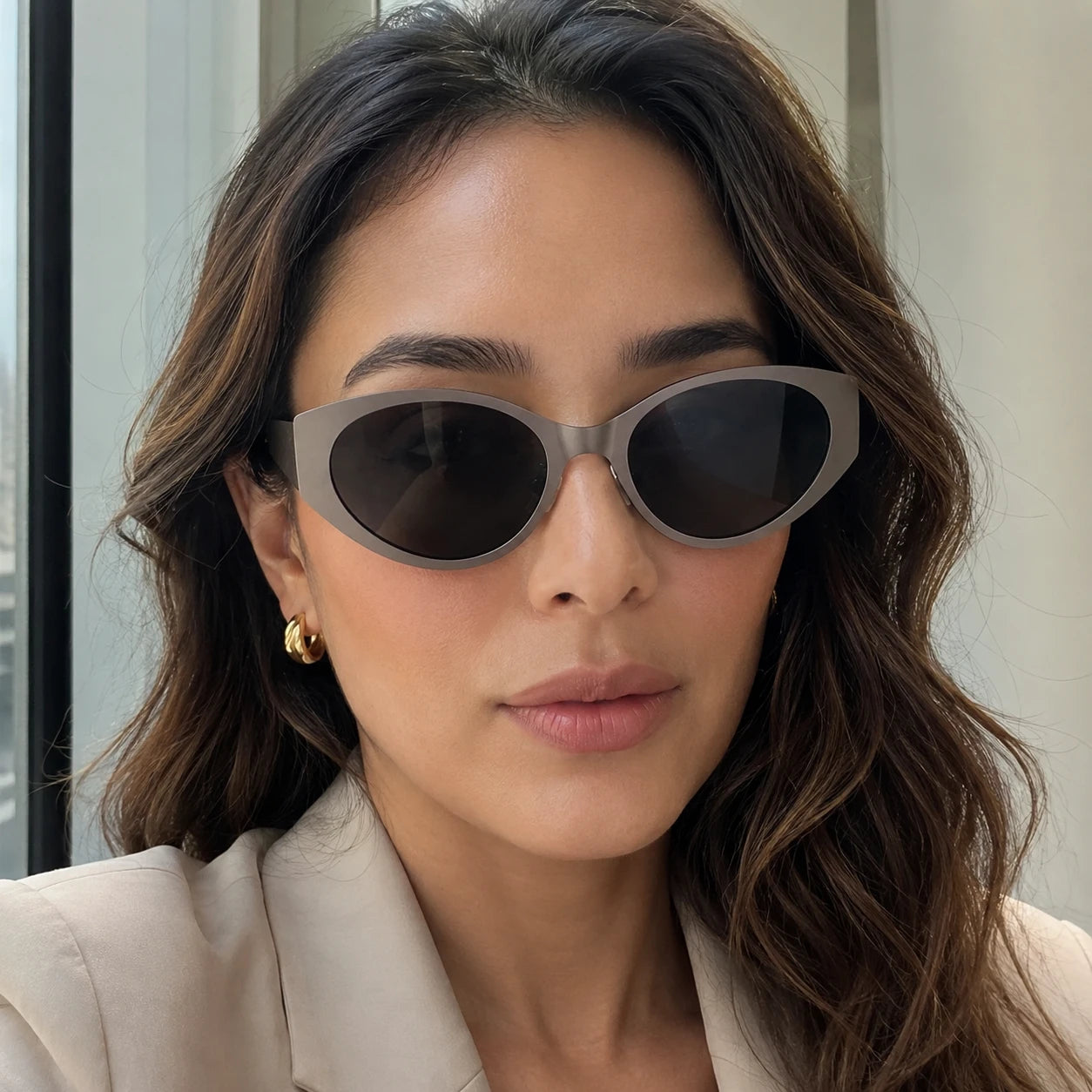 Lyra cat-eye sunglasses with cool stone gray frames and dark solid lenses worn by a woman looking at the camera.
