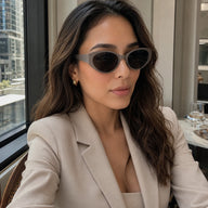 A stylish woman in a beige blazer wearing Lyra neutral gray retro sunglasses inside a modern venue.