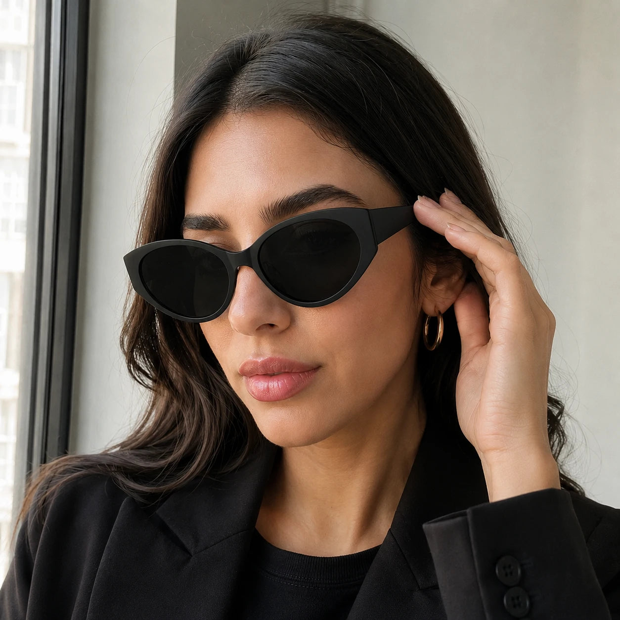 Close-up of a brunette woman adjusting her Lyra dark-tinted black acetate sunglasses.