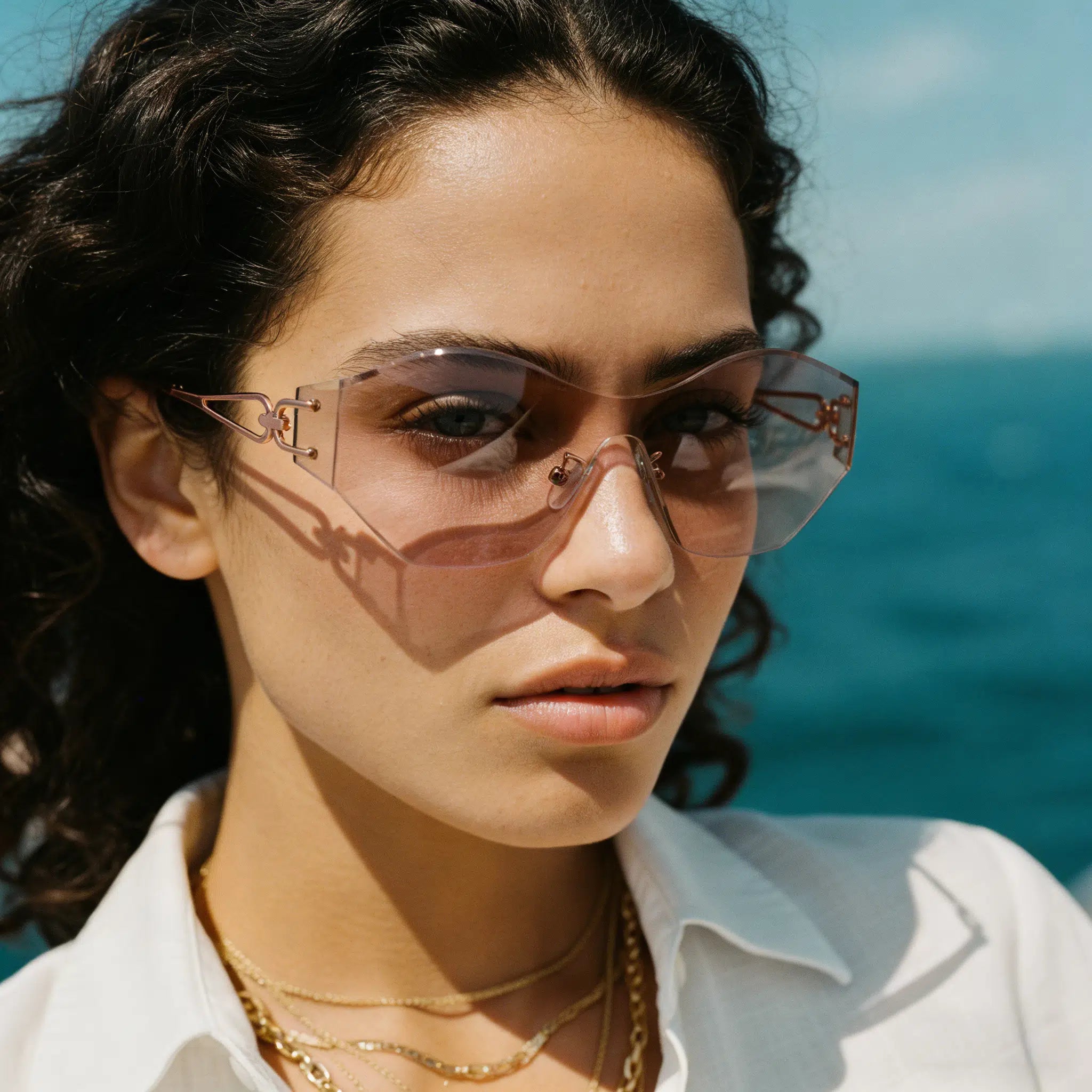 Woman wearing sunglasses with a blurred ocean background