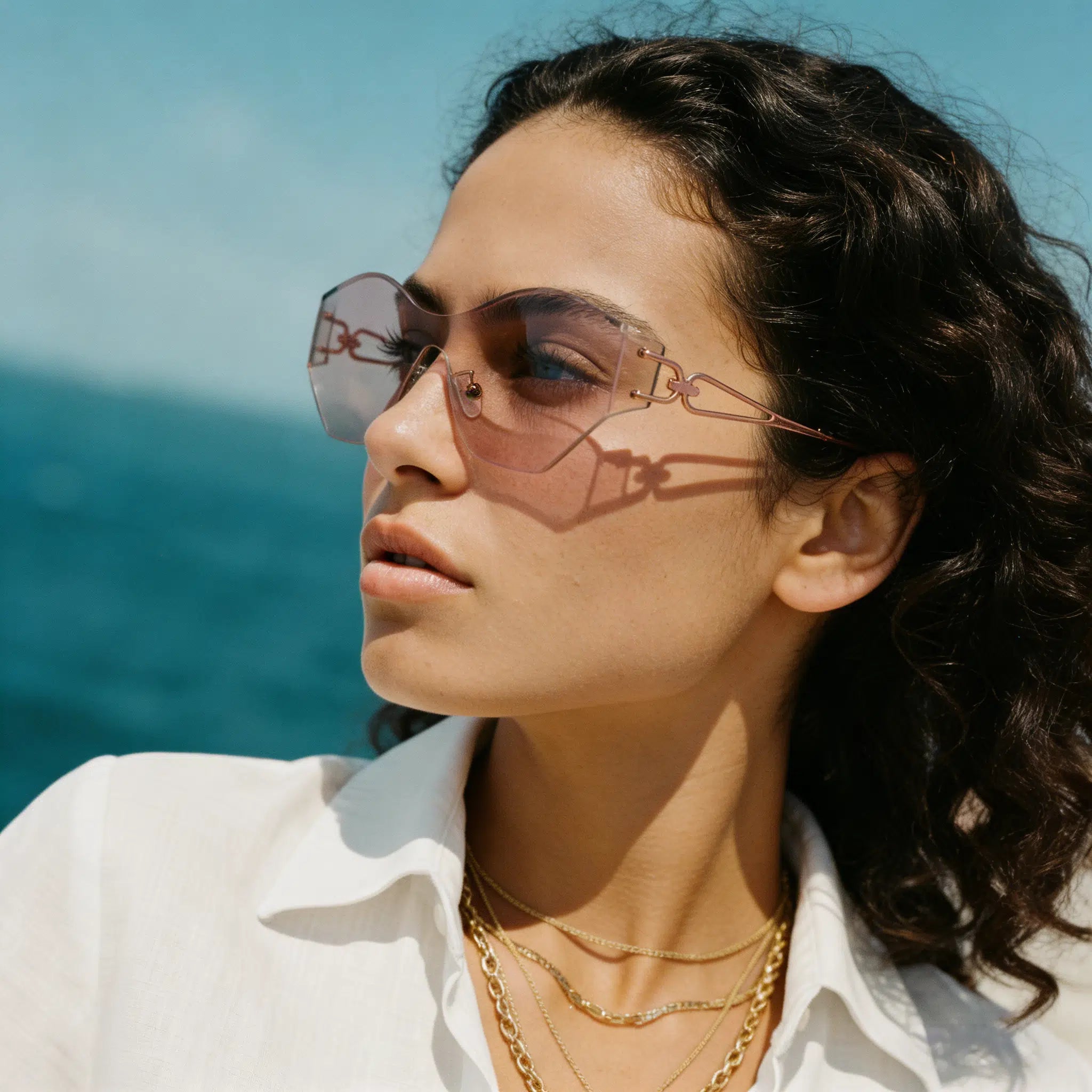 Woman wearing sunglasses with a blue sky and ocean background
