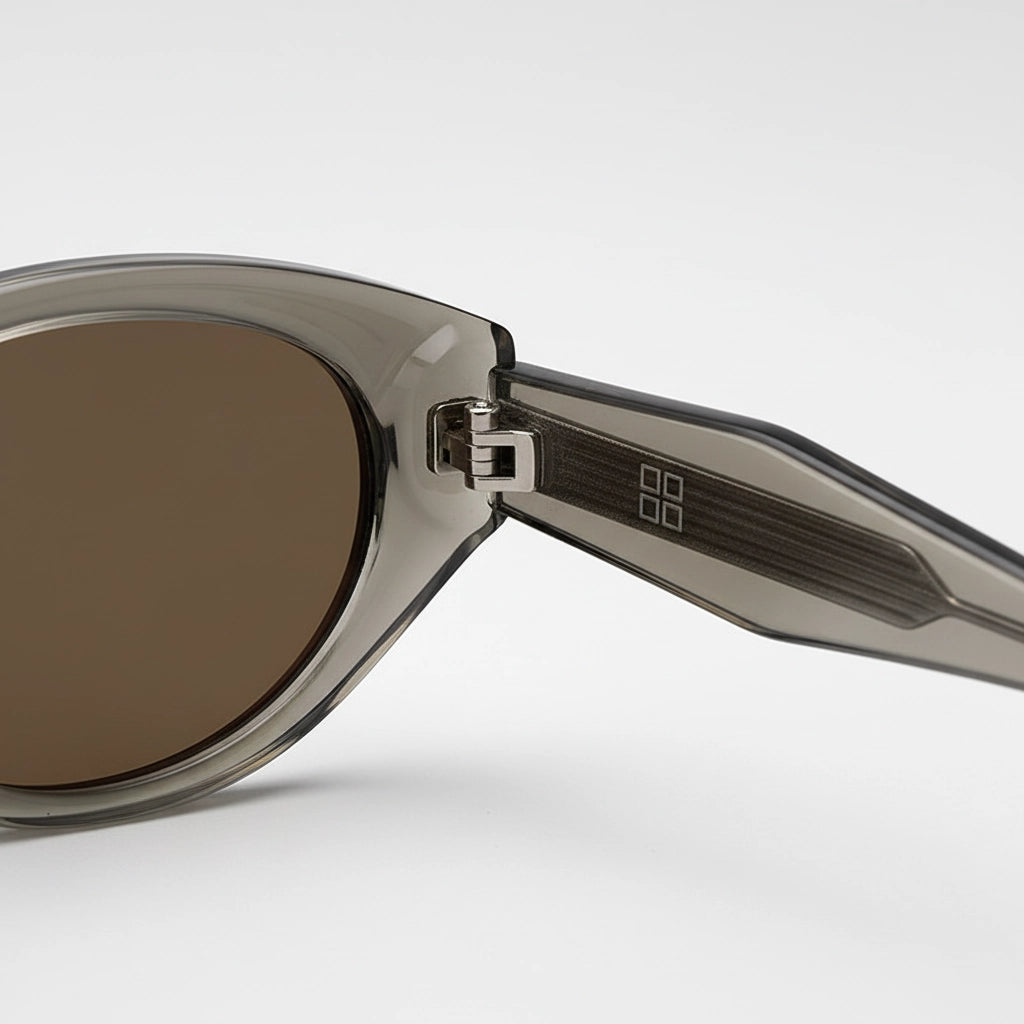 Close-up hinge detail of grey-tea transparent cat-eye sunglasses with silver BB metal logo